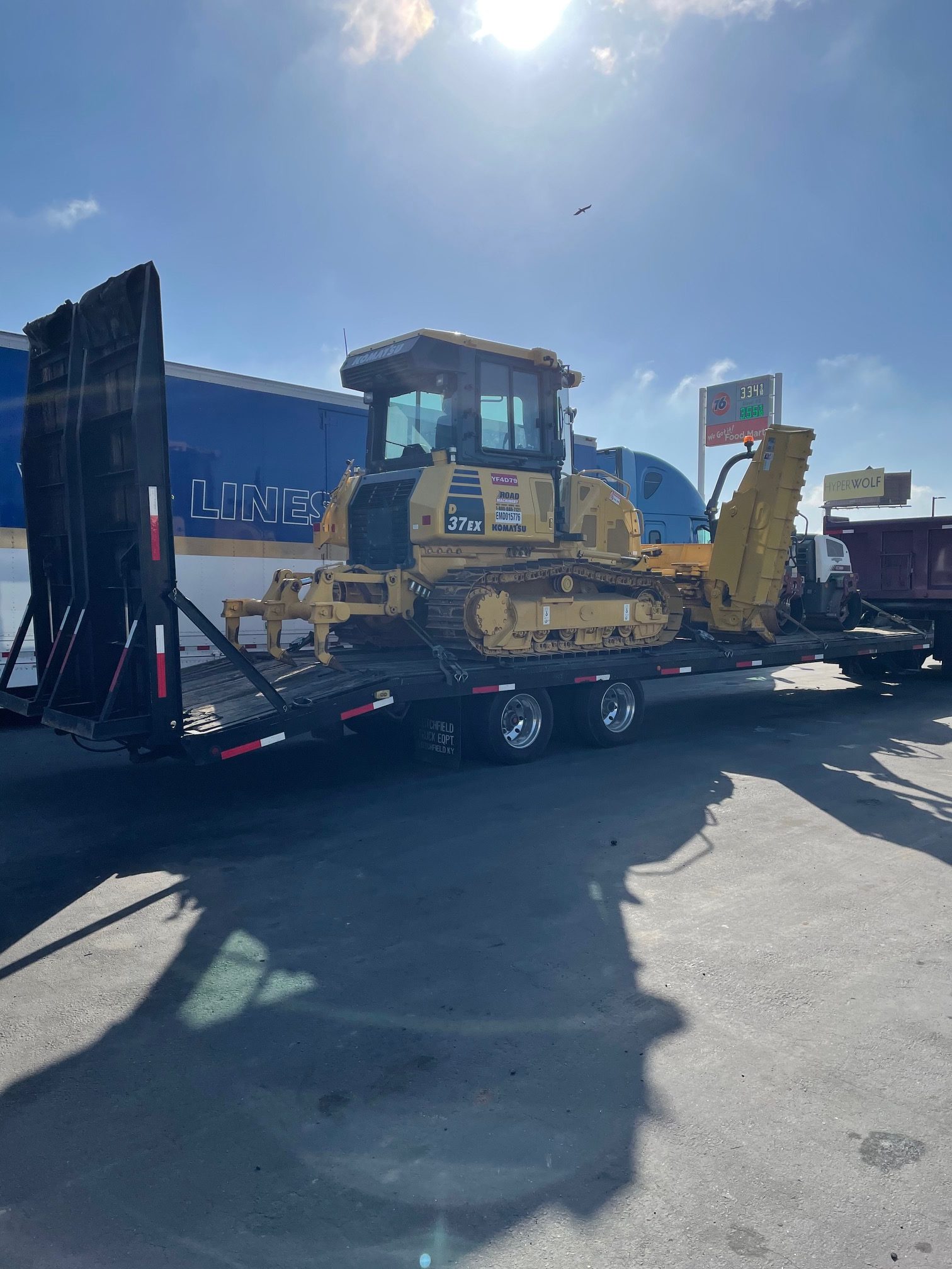 A yellow bulldozer is loaded on a black trailer