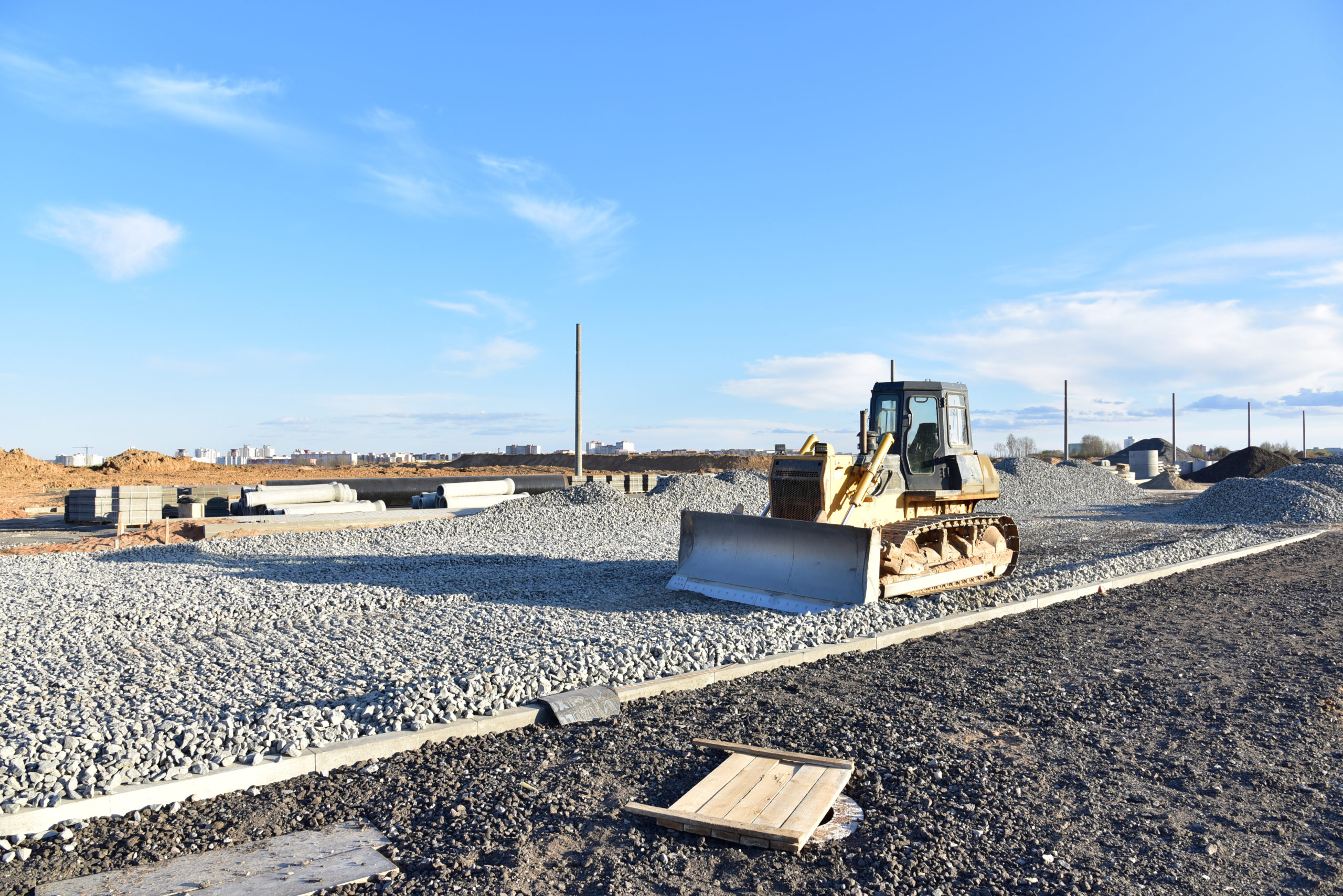 A bulldozer at a road construction site, with work in progress under a clear sky